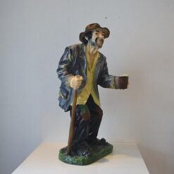 Kerjäläinen patsas, keppi kädessä ja kuvattu sivulta